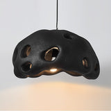 Black perforated dome shade photographed against a pale ground