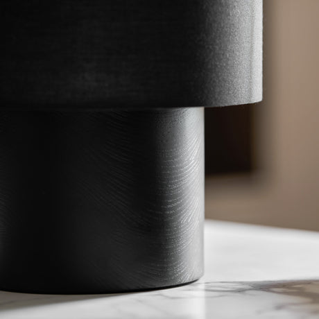 Close view of the brushed black wood plinth and the dark shade