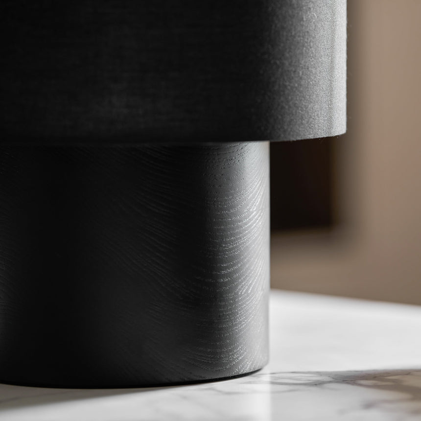 Close view of the brushed black wood plinth and the dark shade
