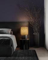 Wabi sabi table lamp lit on a nightstand in a dark bedroom
