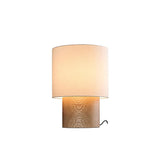 Wabi sabi table lamp in light wood lit against a plain ground