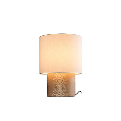 Wabi sabi table lamp in light wood lit against a plain ground