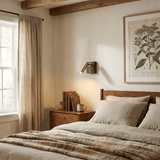 Reading lamp lit on a bedroom wall beside a window and a wood bed frame