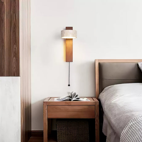 Lamp lit above a walnut nightstand with a small plant beside a made bed