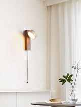 Lamp lit beside a sheer curtain above a table with a hat and a glass vase