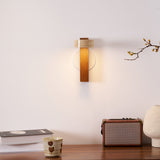 Lamp lit above a desk holding an open book, a radio and a pale vase