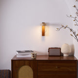 Lamp lit above a walnut sideboard with books, a cup and a small frame