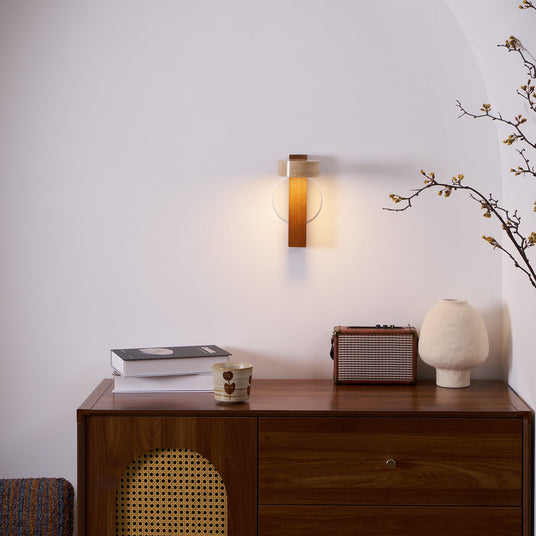 Lamp lit above a walnut sideboard with books, a cup and a small frame