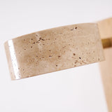 The pitted edge of the travertine drum lit warm from inside the head
