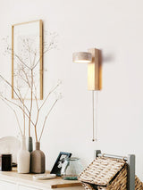 Lamp lit above a shelf of pale vases, framed prints and a woven basket