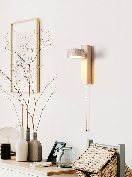 Lamp lit above a shelf of pale vases, framed prints and a woven basket