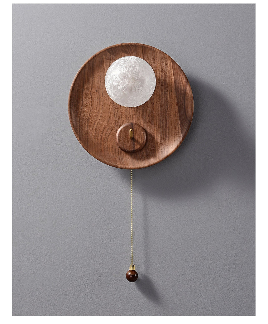 The globe lit on a gray wall, the walnut disc dark around it