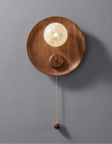 The walnut disc unlit, the textured globe pale against the grain