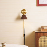 Walnut sconce lit beside a framed print above a caned chair