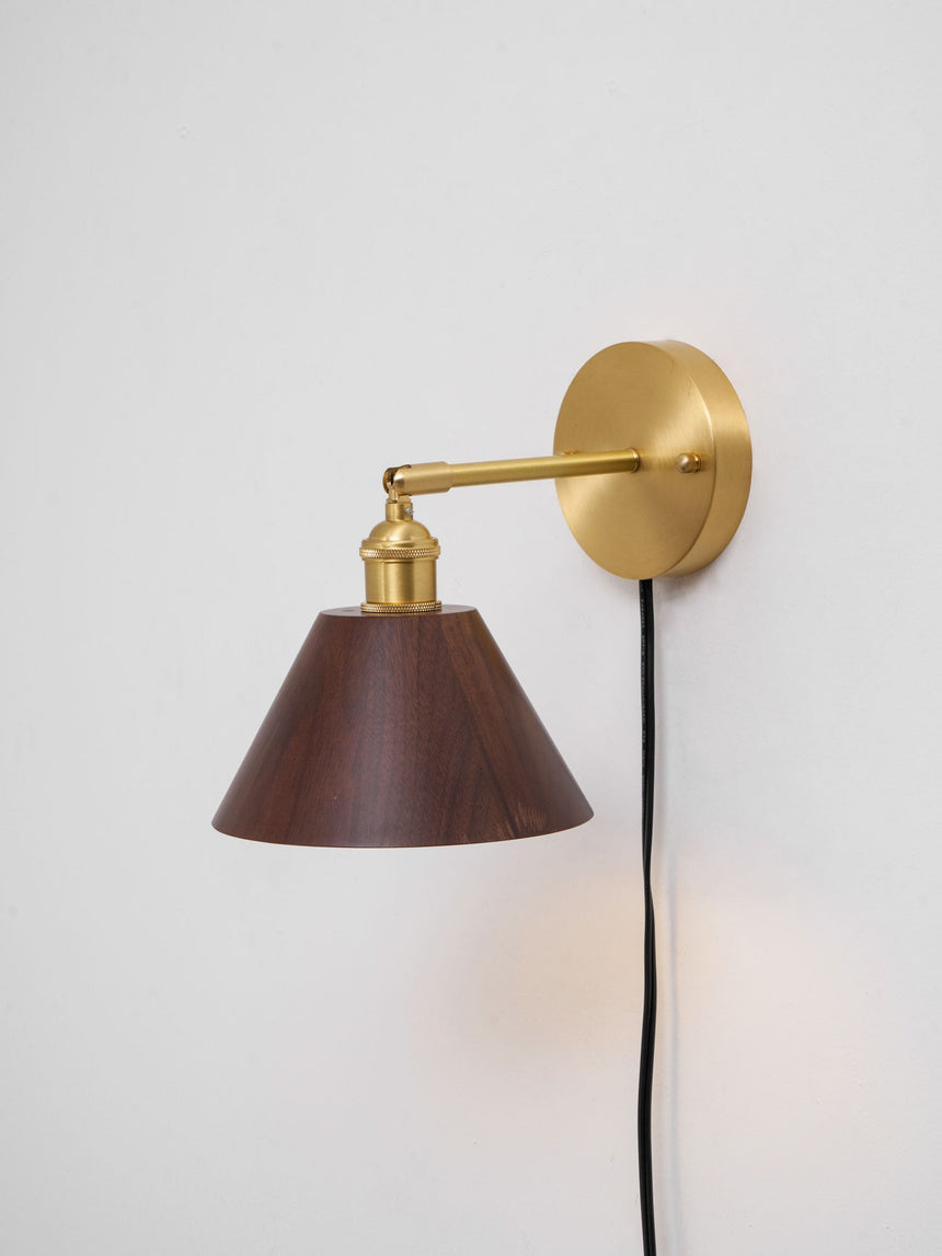 Walnut cone sconce seen at an angle on a plain wall