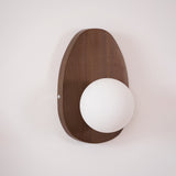 Walnut oval sconce seen at an angle, the glass sphere proud of the plate