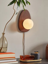Sconce on a wall above a table with books and a small tray