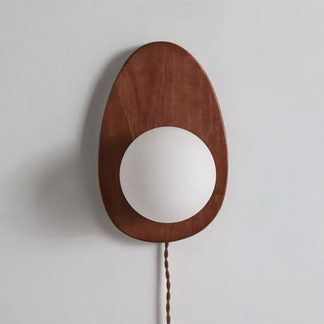 Unlit walnut oval sconce on a pale gray wall, seen from the front