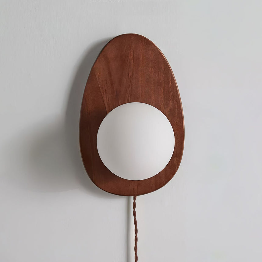 Unlit walnut oval sconce on a pale gray wall, seen from the front