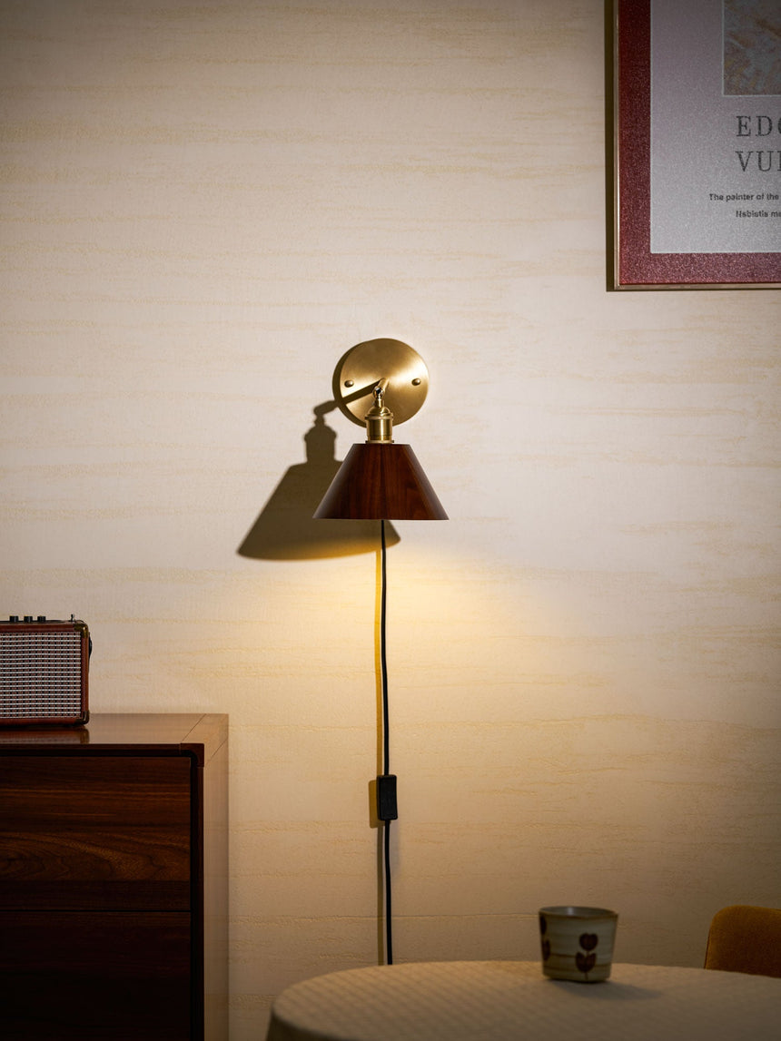 Sconce lit above a small round table beside a wood cabinet