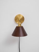 Close view of the round brass wall plate and the cord exit