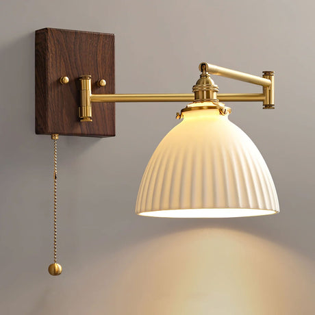 Wide rounded ceramic shade lit, seen from the side on a brass arm