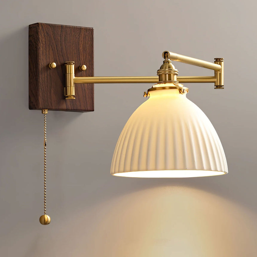 Wide rounded ceramic shade lit, seen from the side on a brass arm
