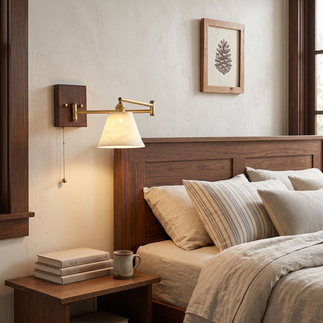 Ceramic wall lamp lit above a wood bed with books on the nightstand