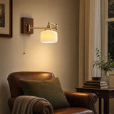 Ceramic wall lamp lit beside a leather armchair in a reading corner