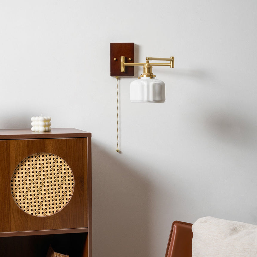Small white ceramic shade on a brass arm beside a cane fronted cabinet