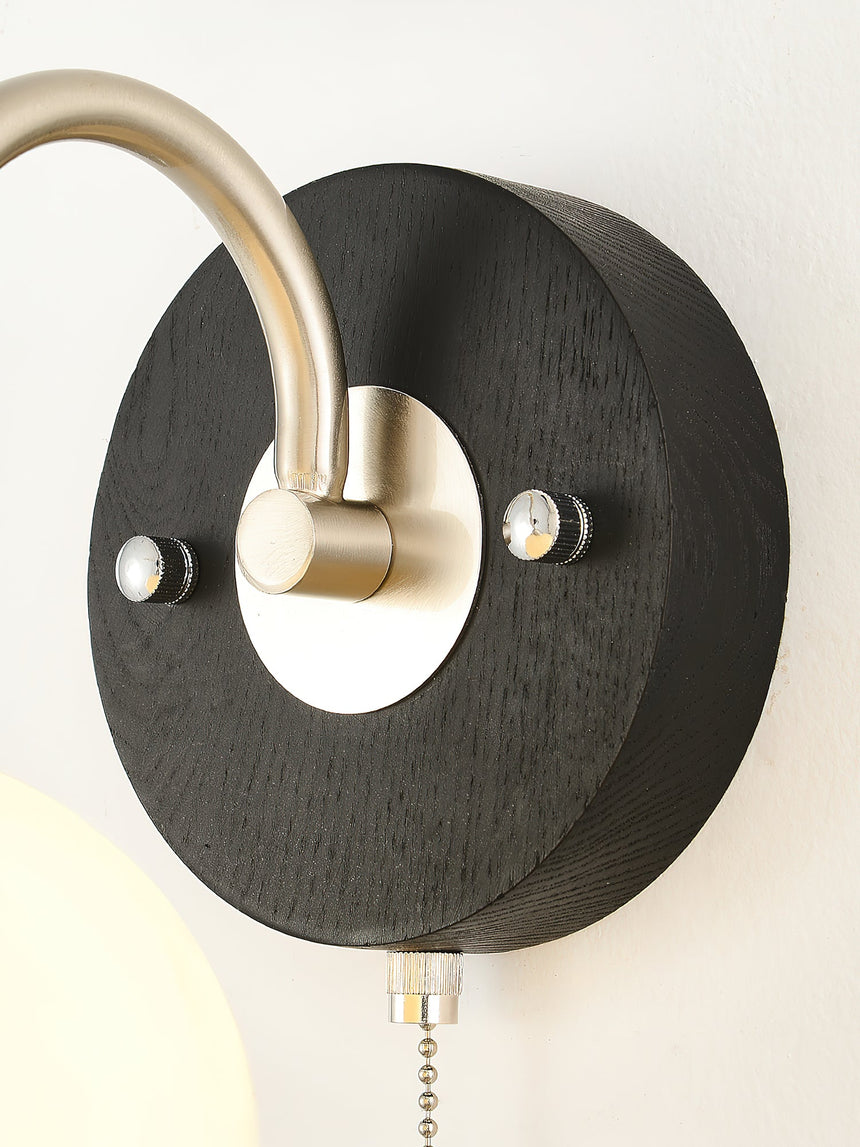 The round black wood backplate with the nickel arm leaving its middle