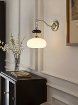 Lamp lit in a hallway above a dark cabinet holding a vase of branches