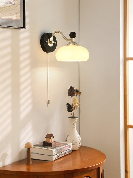 Lamp lit above a round wood table with books and a small vase of flowers