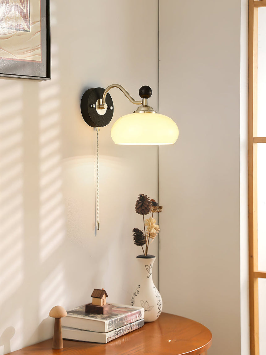 Lamp lit above a side table stacked with books beside a bright window
