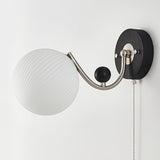 A swirled white glass shade seen unlit from the front on its arm