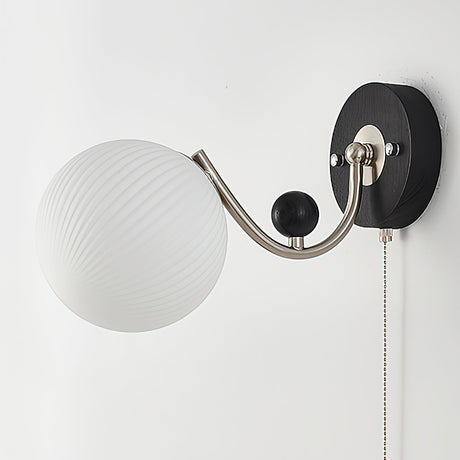 A swirled white glass shade seen unlit from the front on its arm