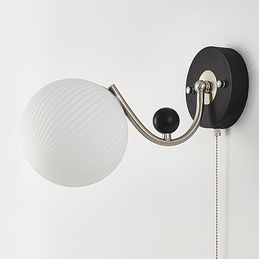 A swirled white glass shade seen unlit from the front on its arm