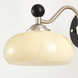 A wide cream glass dome hanging from the curved nickel arm