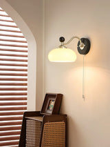Lamp lit beside an arched doorway above a framed print and a cane chair