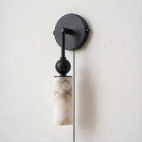 A single black version with its stone tube and cord on a pale wall