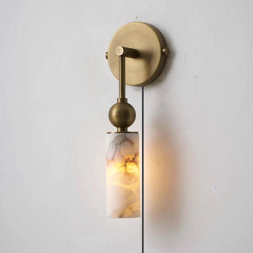 A single brass version lit on a pale wall with its cord hanging