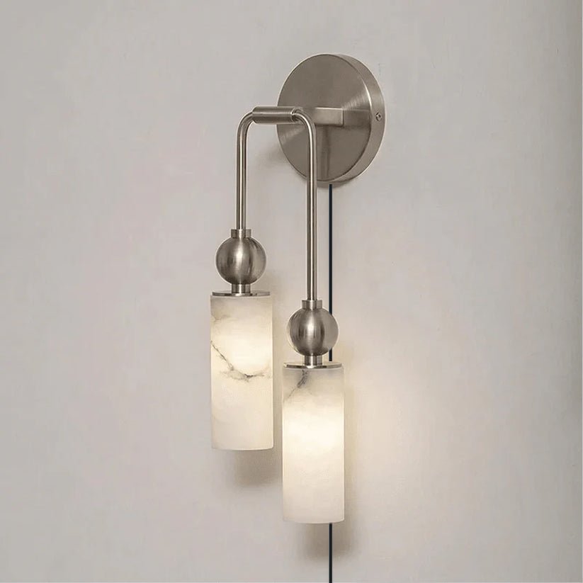 The nickel version with two stone tubes and a cord on a pale wall