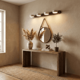 Lit above a console table in a hallway with a round mirror and dried grasses