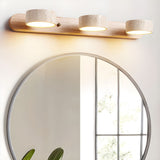 The three travertine shades lit, the stone grain showing against the wood bar