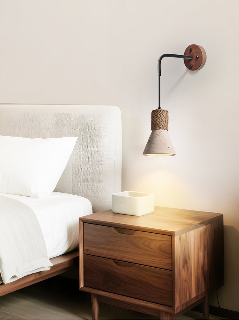 The cone light lit above a walnut nightstand beside a bed with white linens