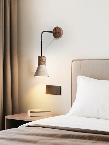 The cone light lit beside an upholstered headboard above a low nightstand