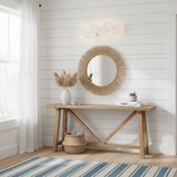 The disc light above a wood console table with a round woven mirror