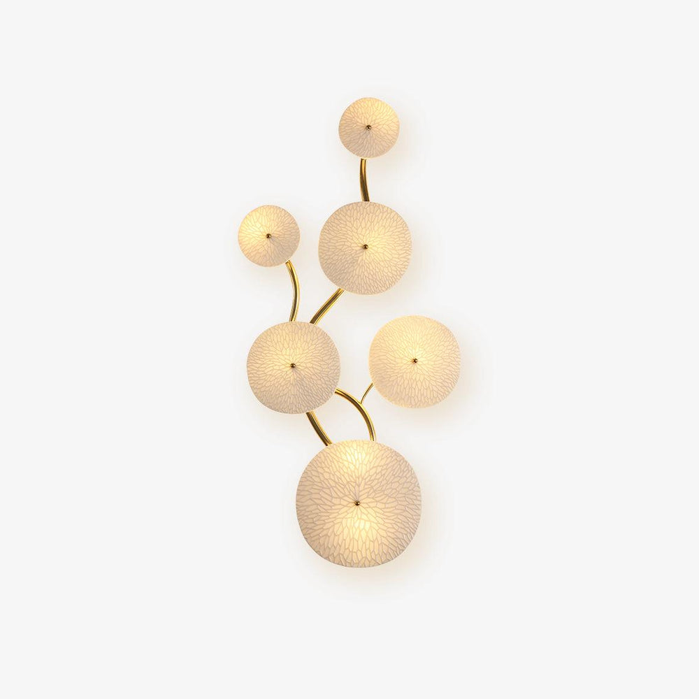 Wall light made of textured white ceramic discs on a curving gold stem, vertical layout
