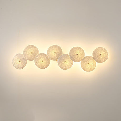 Eight discs in a horizontal row, each glowing warm on a beige wall