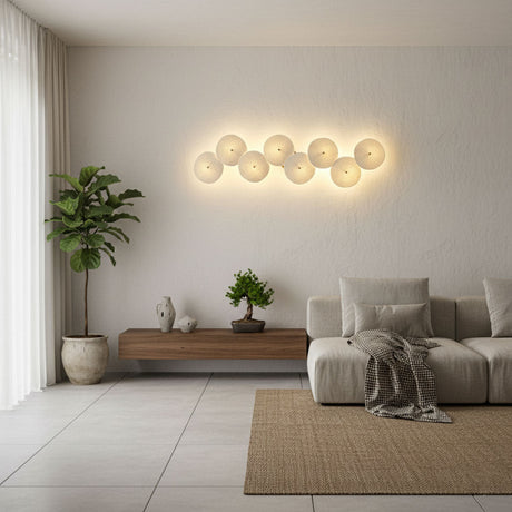 Six discs glowing above a low sofa and a wood console in a bright living room